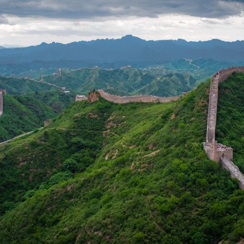 The Great Wall of China winding over green mountain ridges The Great Wall of China winding over green mountain ridges